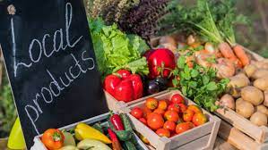 A black board with 'Local Products' on it, surrounded by different vegetables